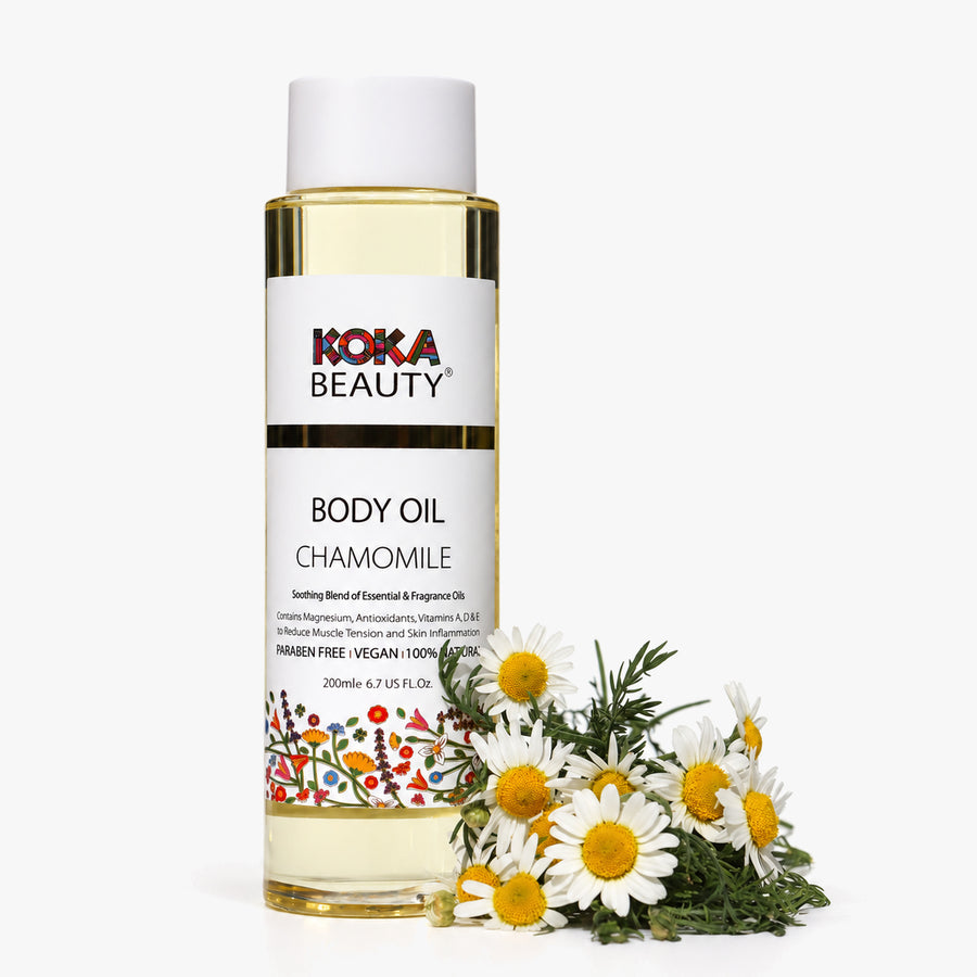 Koka Beauty Chamomile Body Oil bottle styled with fresh chamomile flowers on white