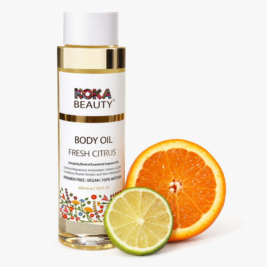 Koka Beauty Fresh Citrus Body Oil bottle beside halved orange and lime on white