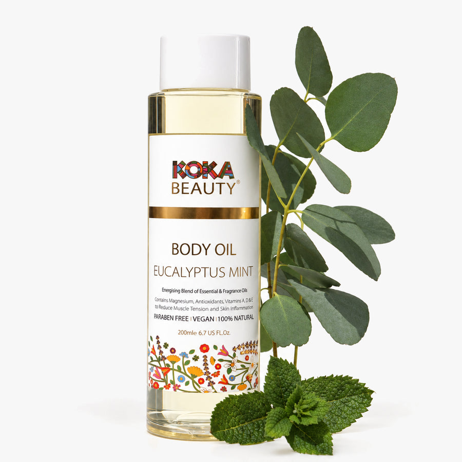 Koka Beauty Eucalyptus Mint Body Oil bottle with eucalyptus leaves and fresh mint on white